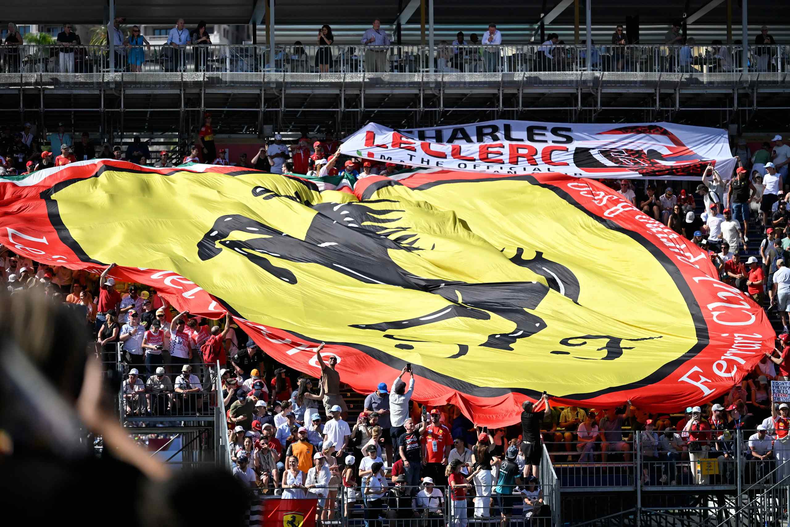 A crowd of race fans unfurls a Ferrari flag.